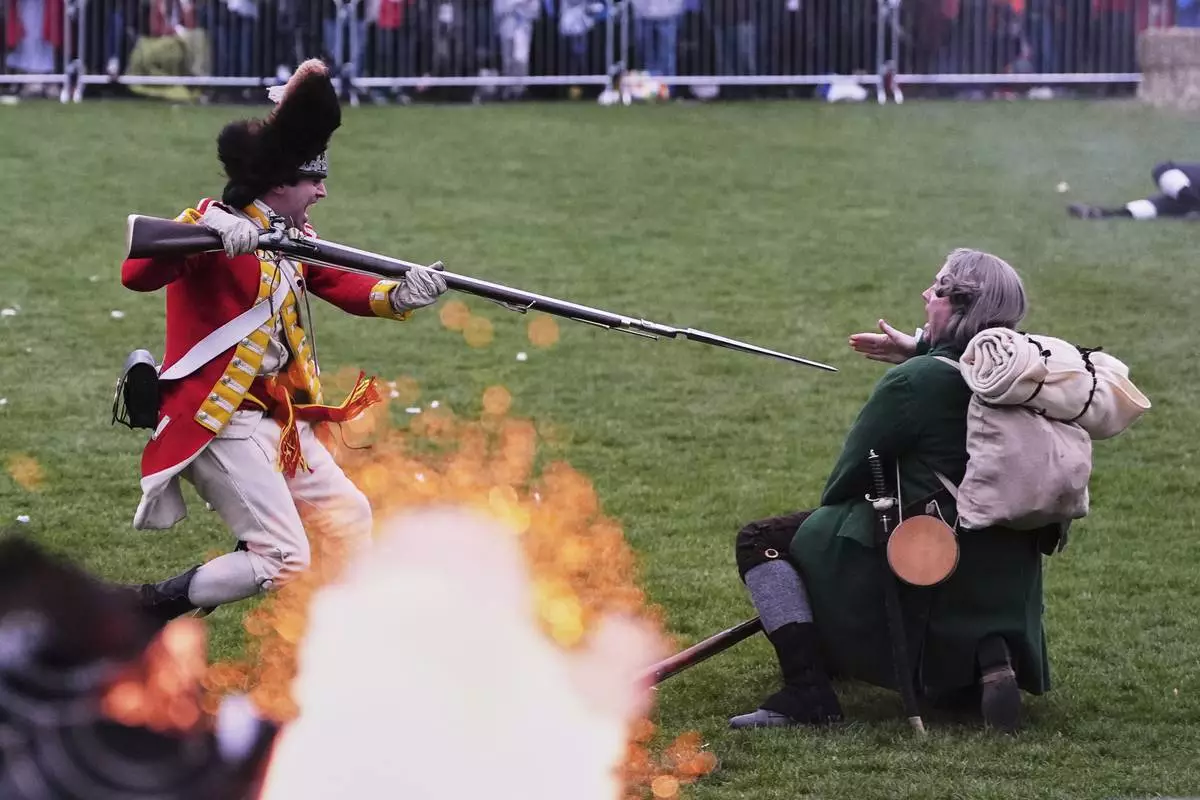 While a rifle fires, a British Regular stabs a New England colonial militia, also known as a Minuteman, during a reenactment celebration of the 250th anniversary of the Battle of Lexington and start of the American Revolution, Saturday, April 19, 2025, in Lexington, Mass. (AP Photo/Charles Krupa)