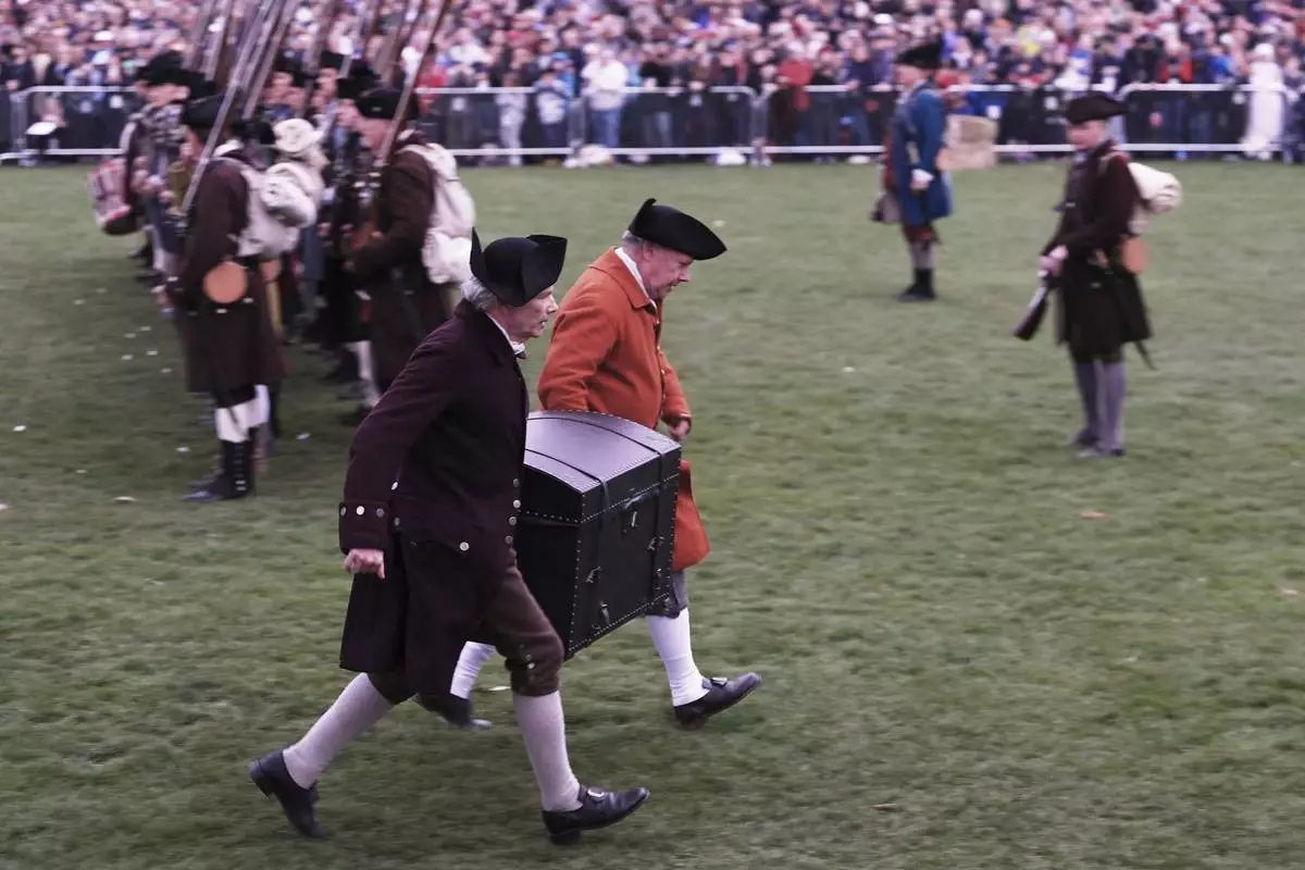 Colonial men carry the papers of John Hancock away from the advancing British Regulars during a reenactment celebration of the 250th anniversary of the Battle of Lexington and start of the American Revolution, Saturday, April 19, 2025, in Lexington, Mass. (AP Photo/Charles Krupa)