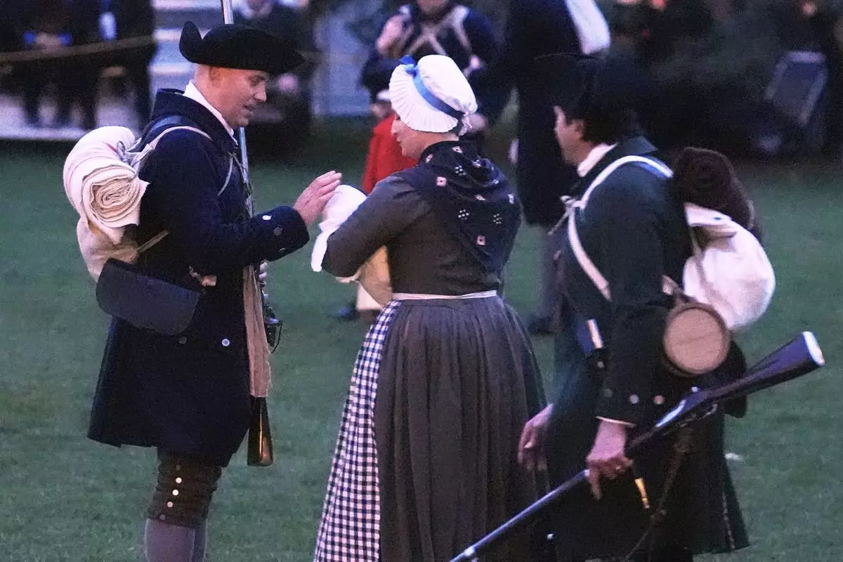 A New England colonial militia man, also known as a Minuteman, caresses the head of a baby prior to facing the British Regulars during a reenactment celebration of the 250th anniversary of the Battle of Lexington and start of the American Revolution, Saturday, April 19, 2025, in Lexington, Mass. (AP Photo/Charles Krupa)