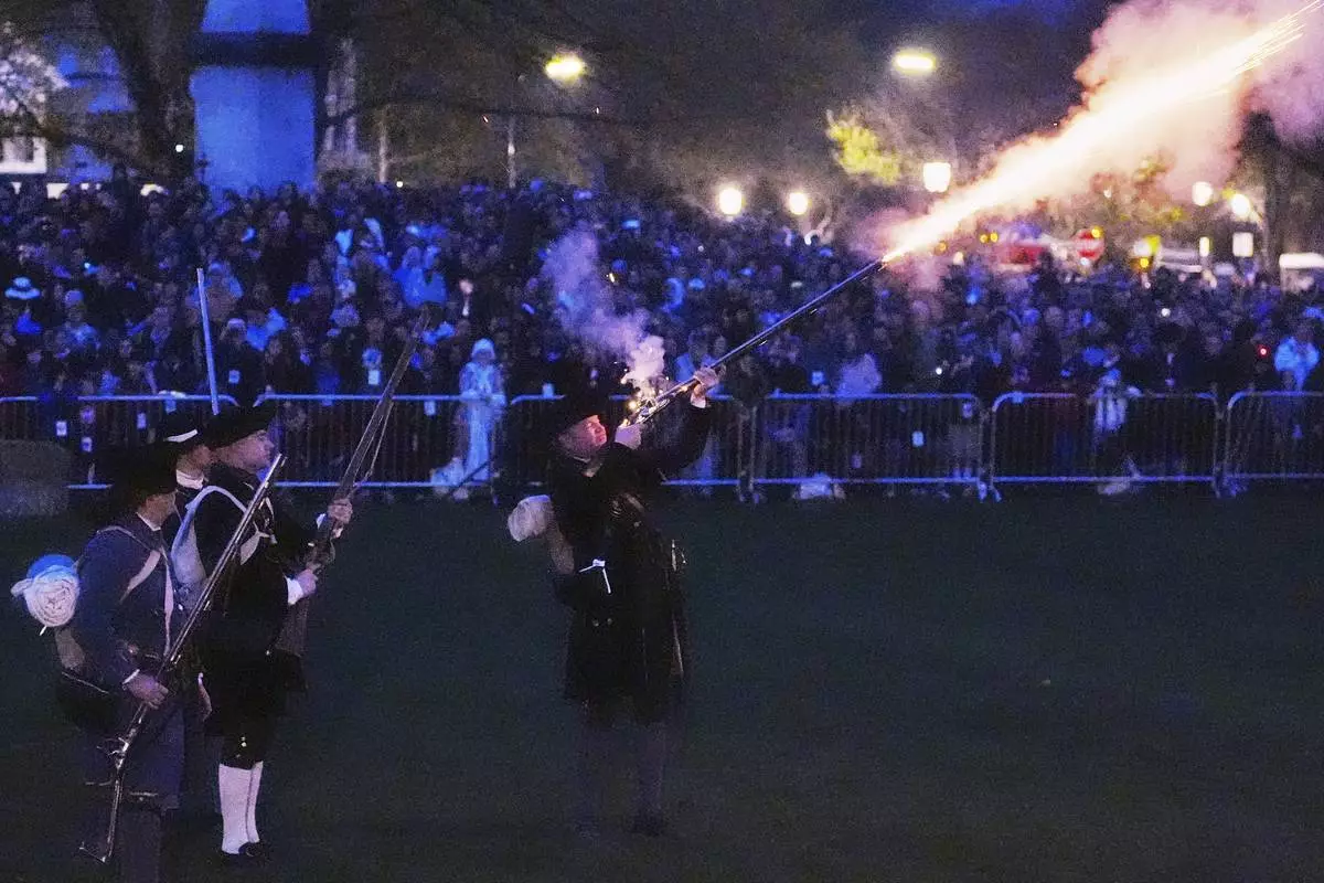 New England colonial militia, also known as a Minuteman, fires a rifle before sunrise during a reenactment celebration of the 250th anniversary of the Battle of Lexington and start of the American Revolution, Saturday, April 19, 2025, in Lexington, Mass. (AP Photo/Charles Krupa)
