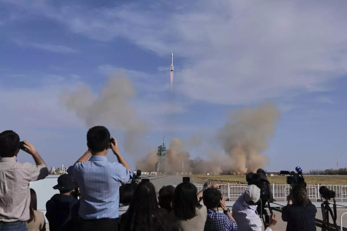 Journalists film China's Long March 2F rocket, carrying three astronauts for the Shenzhou 20 manned space mission, lifts off for a space station, at the Jiuquan Satellite Launch Center in Jiuquan, northwestern China, Thursday, April 24, 2025. (AP Photo/Andy Wong)