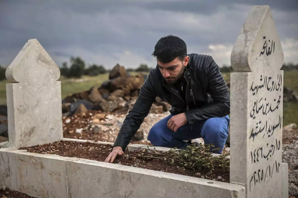 Salah Swed, 28, visits the grave of his brother Mohammed, who was killed while trying to dismantle a landmine, in their village of Kafr Nabl, south of Idlib, Syria, Monday, April 14, 2025. (AP Photo/Ghaith Alsayed)