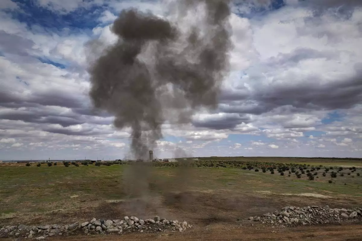 Smoke billows as a landmine is detonated during a ministry of defence operation to clear explosives left behind by the Syrian army during the war, in agricultural land south of Idlib, Syria, Sunday, April 13, 2025. (AP Photo/Ghaith Alsayed)