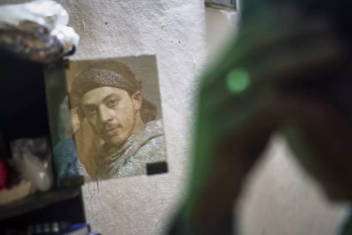 Suleiman Khalil, 21, who lost his leg in a landmine explosion while harvesting olives with his friends in a field, is reflected in a mirror at his home in the village of Qaminas, east of Idlib, Syria, Wednesday April 9, 2025. (AP Photo/Ghaith Alsayed)