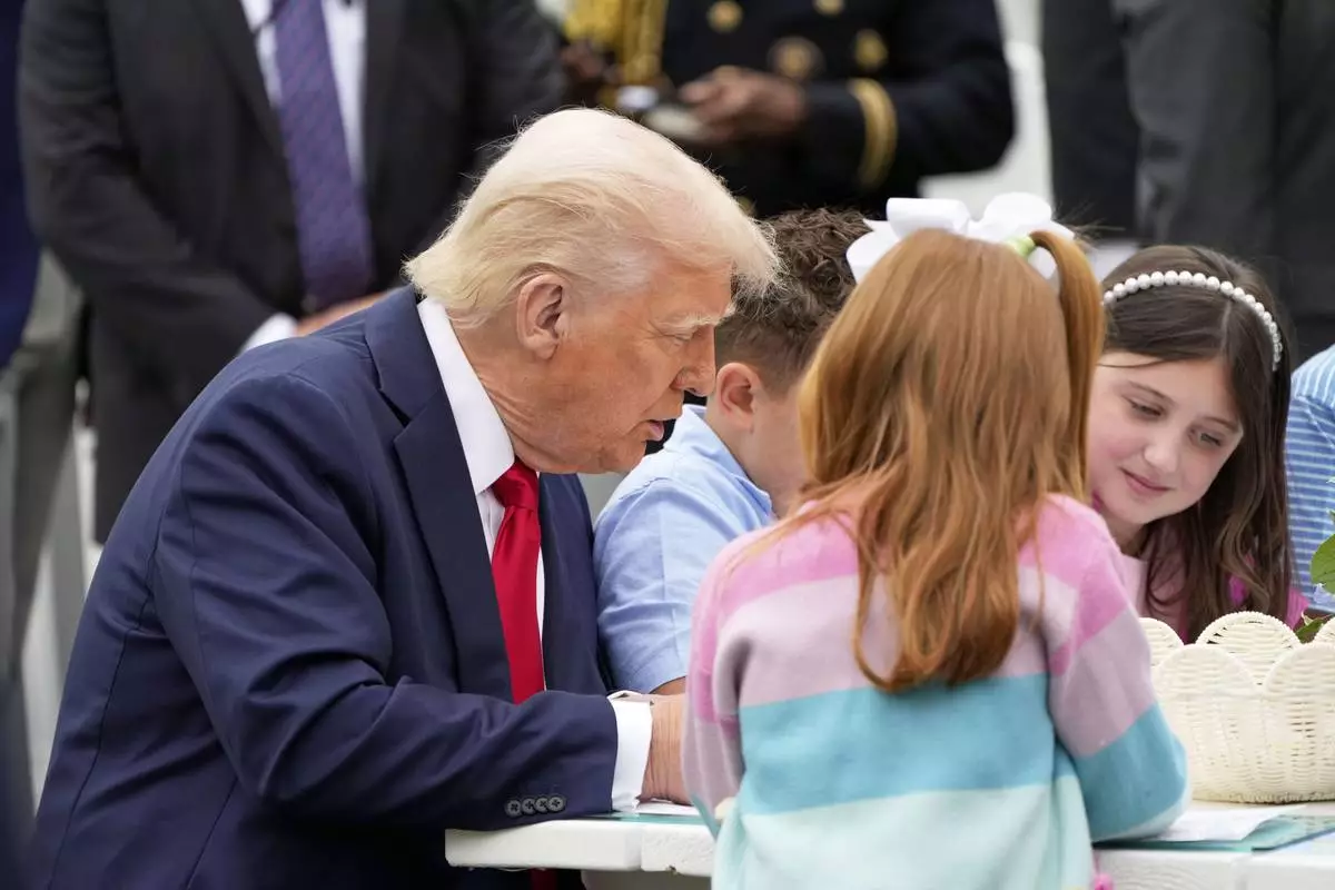 President Donald Trump sits with children as he participates in the White House Easter Egg Roll on the South Lawn of the White House, Monday, April 21, 2025, in Washington. (AP Photo/Mark Schiefelbein)