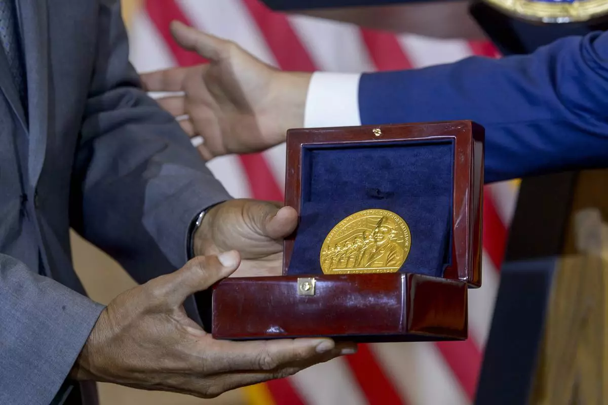 House Speaker Mike Johnson, R-La., right, presents the Congressional Gold Medal to Stanley Earley III, son of Lt. Col. Charity Adams Earley, left, during a ceremony honoring the Six Triple Eight, on Capitol Hill, Tuesday, April 29, 2025, in Washington. The U.S. Army's 6888th Central Postal Directory Battalion, also known as the Six Triple Eight, was a group of Black servicewomen, serving overseas, to sort millions of pieces of mail and deliver them to the troops in the field of battle during World War II. (AP Photo/Rod Lamkey, Jr.)