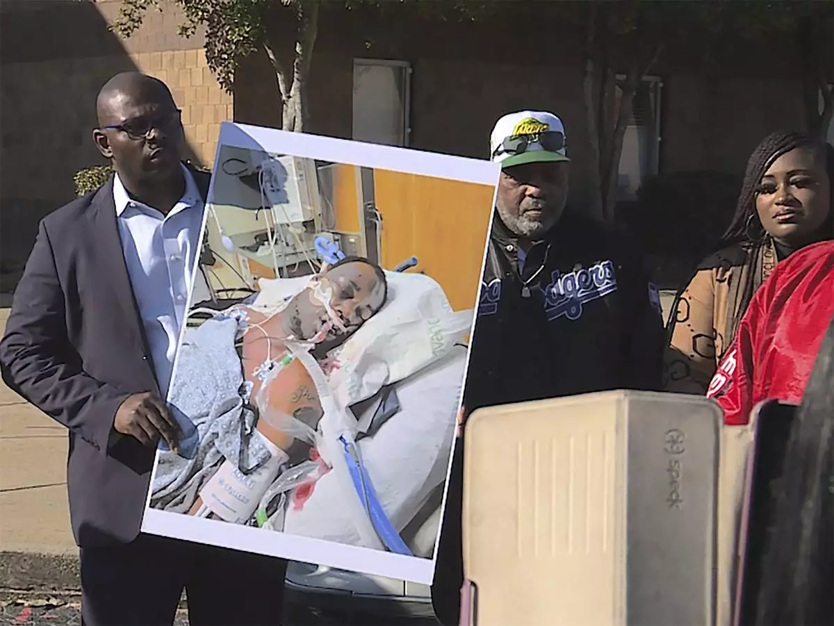 FILE - In this photo provided by WREG, Tyre Nichols' stepfather Rodney Wells, center, stands next to a photo of Nichols in the hospital after his arrest, during a protest in Memphis, Tenn., Jan. 14, 2023. (Jordan James/WREG via AP)