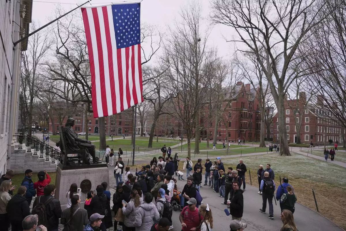 Visitors stop at the statue of John Harvard in Harvard Yard at Harvard University, Tuesday, April 15, 2025, in Cambridge, Mass. (AP Photo/Charles Krupa)