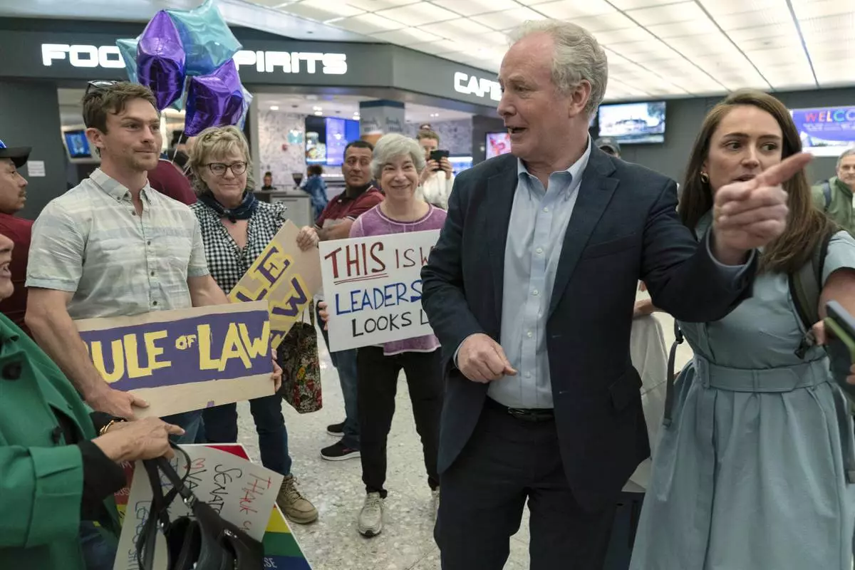 Sen. Chris Van Hollen, D-Md., is welcomed by supporters upon his arrival from meeting with Kilmar Abrego Garcia in El Salvador, at Washington Dulles International Airport, in Chantilly, Va., Friday, April 18, 2025. (AP Photo/Jose Luis Magana)