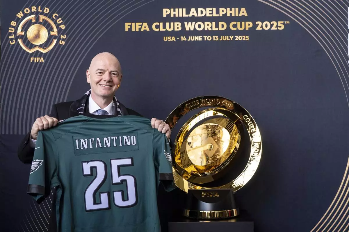 FIFA President Gianni Infantino poses with a Philadelphia Eagles NFL football jersey while next to the trophy at a welcoming event for the 2025 FIFA Club World Cup soccer tournament, Thursday, April 10, 2025, in Philadelphia. (AP Photo/Chris Szagola)