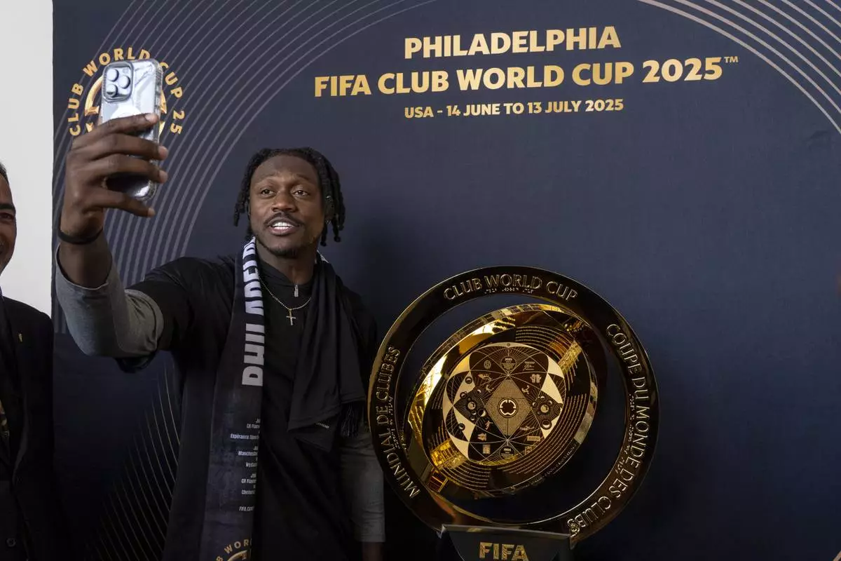 Philadelphia Eagles NFL football player A.J. Brown takes a selfie as he poses with the trophy at a welcoming event for the 2025 FIFA Club World Cup soccer tournament, Thursday, April 10, 2025, in Philadelphia. (AP Photo/Chris Szagola)