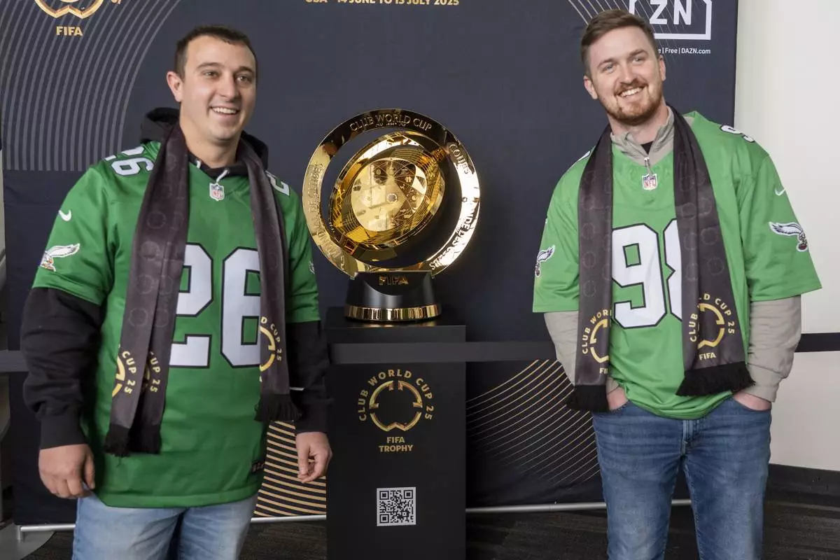 Fans pose with the trophy at a welcoming event for the 2025 FIFA Club World Cup soccer tournament, Thursday, April 10, 2025, in Philadelphia. (AP Photo/Chris Szagola)