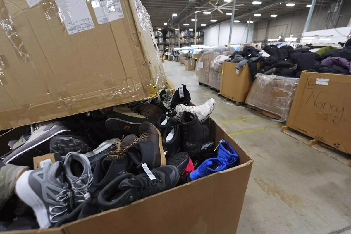 Boxes of returned or overstocked clothing, shoes, boots, coats, packs and other items sit in a warehouse where the goods are cleaned or repaired before they are marketed on resale platforms Thursday, April 17, 2025, in Englewood, Colo. (AP Photo/David Zalubowski)