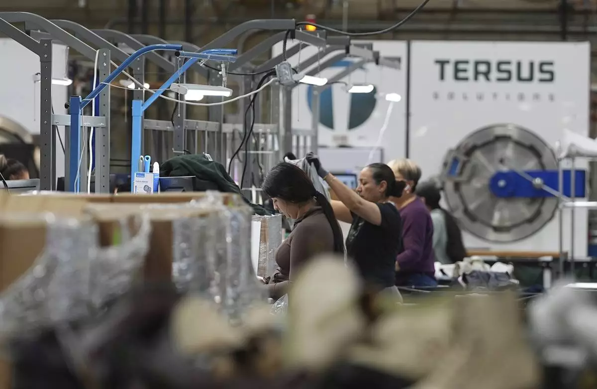 People work amid boxes of returned or overstocked clothing, shoes, boots, coats, packs and other items in a warehouse where the goods are cleaned or repaired before they are marketed on resale platforms in Englewood, Colo., on Thursday, April 17, 2025. (AP Photo/David Zalubowski)