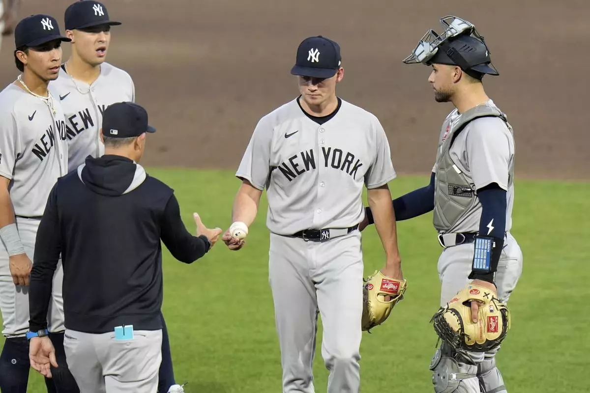 New York Yankees pitcher Will Warren, second from right, hands the ball to manager Aaron Boone as he is taken out of the game against the Tampa Bay Rays during the second inning of a baseball game Thursday, April 17, 2025, in Tampa, Fla. (AP Photo/Chris O'Meara)