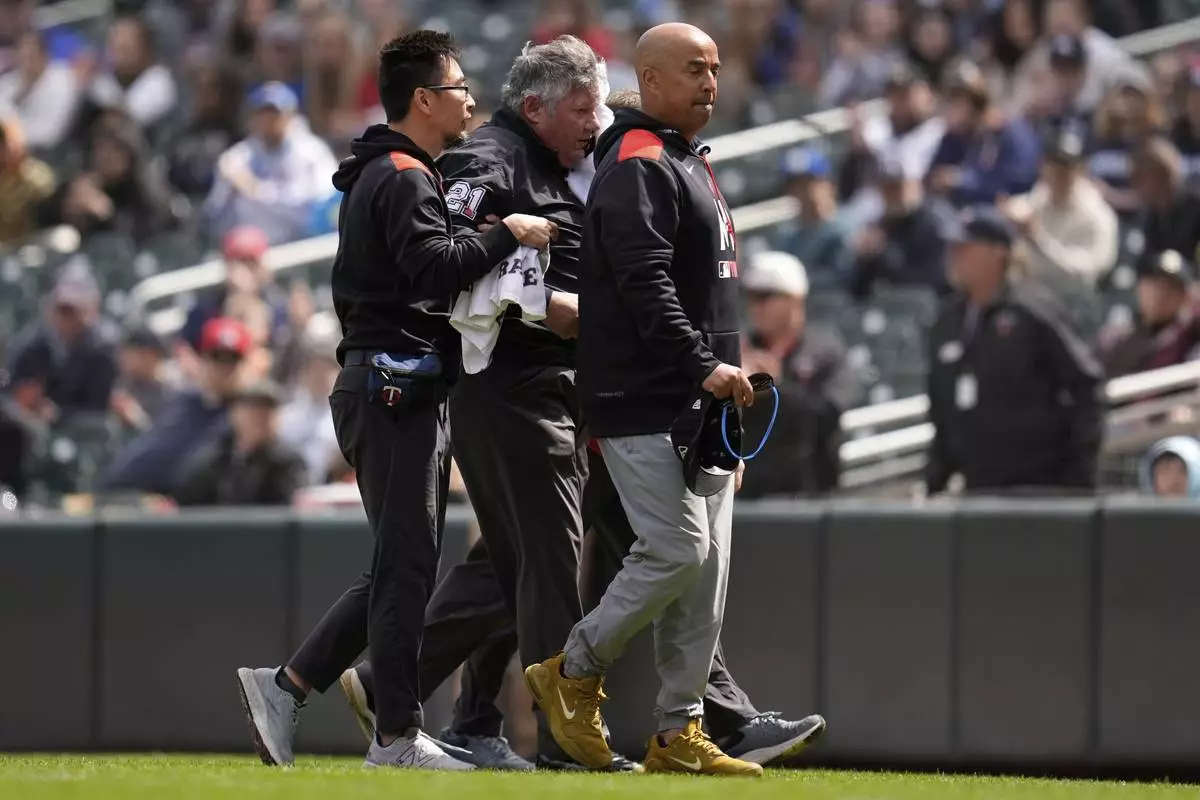 First base umpire Hunter Wendelstedt, center, walks off the field with medical staff after being hit by a foul ball during the seventh inning of a baseball game between the Minnesota Twins and New York Mets, Wednesday, April 16, 2025, in Minneapolis. (AP Photo/Abbie Parr)