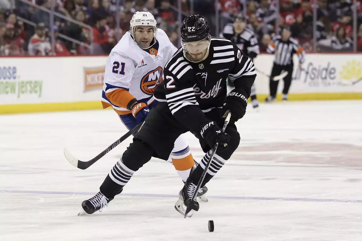 New Jersey Devils defenseman Brett Pesce (22) skates with the puck past New York Islanders center Kyle Palmieri in the third period of an NHL hockey game Sunday, April 13, 2025, in Newark, N.J. (AP Photo/Adam Hunger)