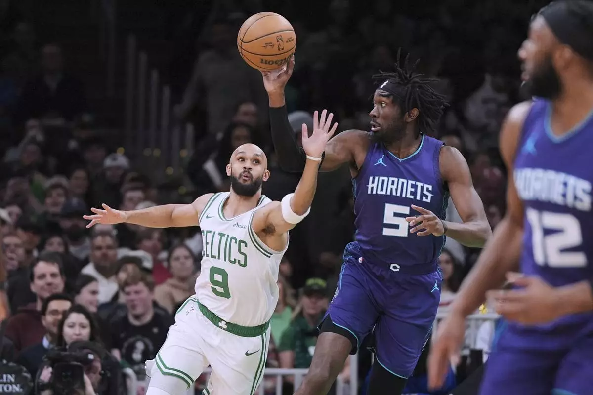 Boston Celtics guard Derrick White (9) tries to steal the ball from Charlotte Hornets center Mark Williams (5) during the first half of an NBA basketball game, Friday, April 11, 2025, in Boston. (AP Photo/Charles Krupa)
