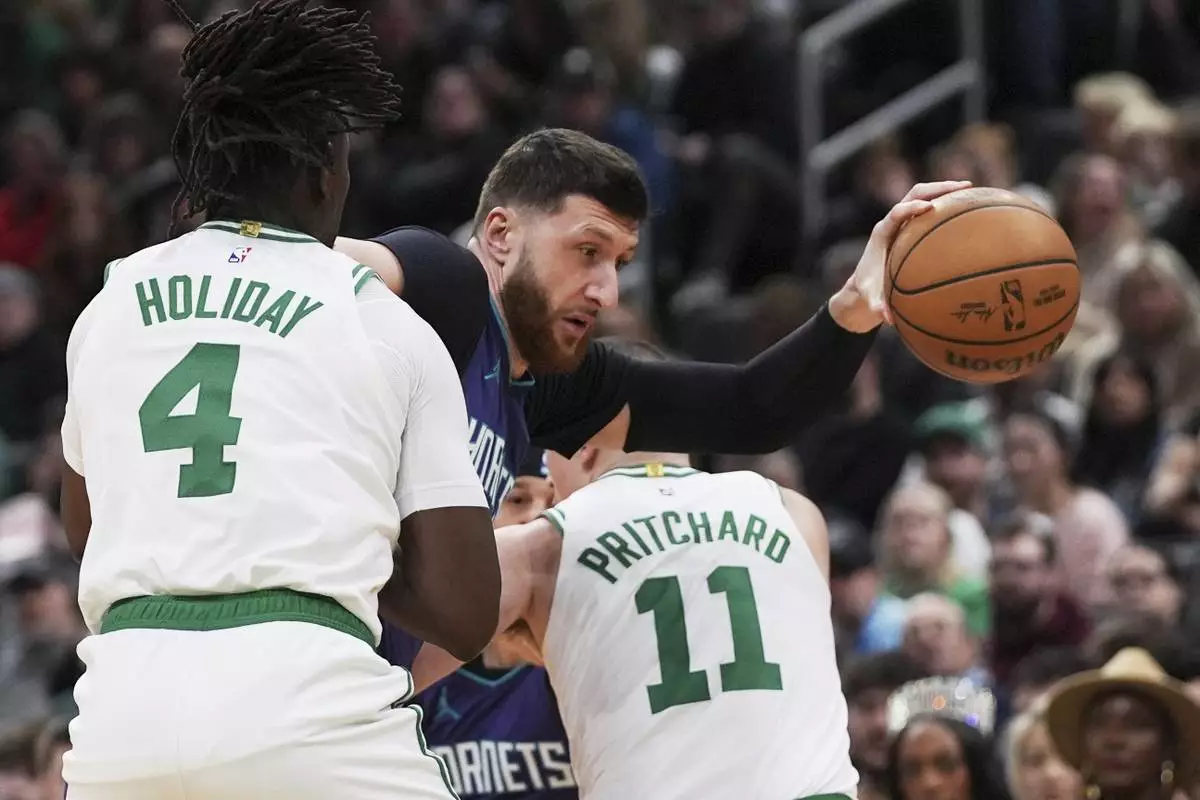 Charlotte Hornets center Jusuf Nurkic, center, gets trapped by Boston Celtics' Jrue Holiday (4) and Payton Pritchard (11) during the first half of an NBA basketball game, Friday, April 11, 2025, in Boston. (AP Photo/Charles Krupa)