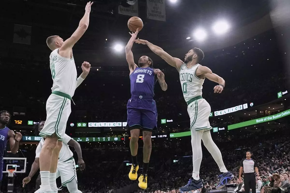 Charlotte Hornets guard Nick Smith Jr. (8) drives to the basket past Boston Celtics forward Jayson Tatum (0) and center Kristaps Porzingis (8) during the first half of an NBA basketball game, Friday, April 11, 2025, in Boston. (AP Photo/Charles Krupa)
