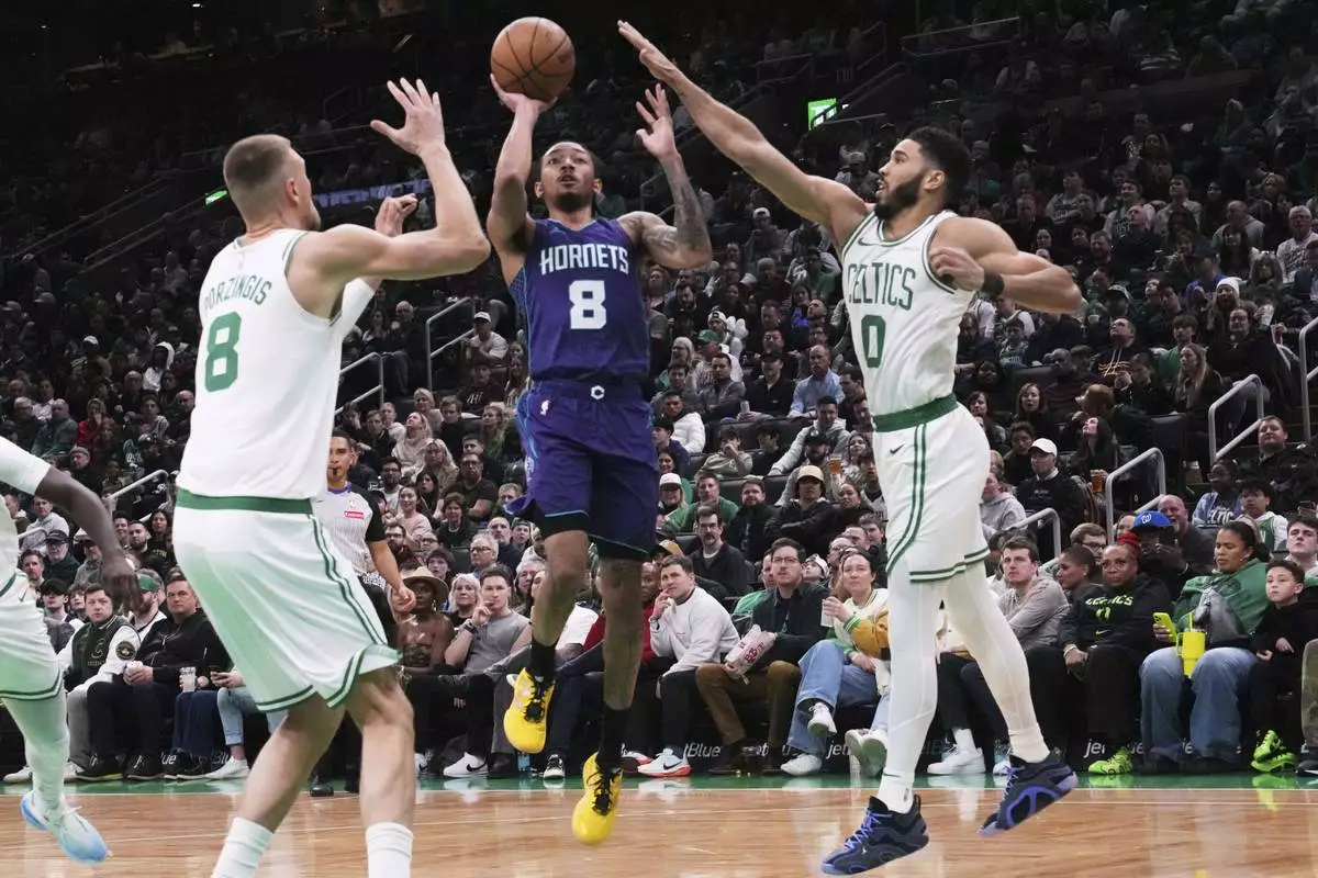 Charlotte Hornets guard Nick Smith Jr. (8) drives to the basket between Boston Celtics forward Jayson Tatum (0) and center Kristaps Porzingis (8) during the first half of an NBA basketball game, Friday, April 11, 2025, in Boston. (AP Photo/Charles Krupa)