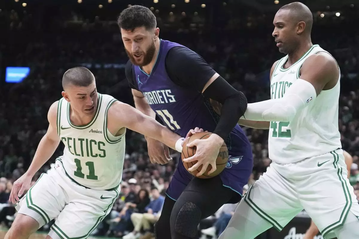 Boston Celtics guard Payton Pritchard, left, tries to steal the ball from Charlotte Hornets center Jusuf Nurkic, center, during the first half of an NBA basketball game, Friday, April 11, 2025, in Boston. (AP Photo/Charles Krupa)