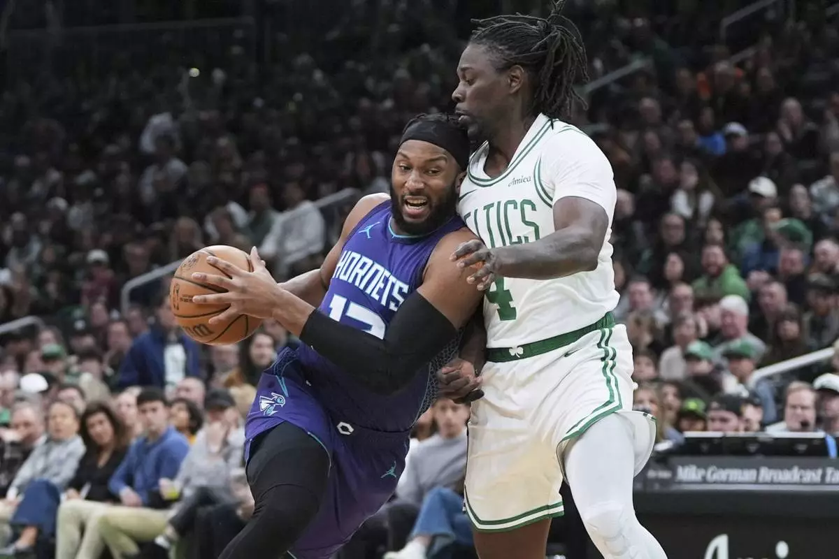 Charlotte Hornets forward Josh Okogie (12) drives to the basket against Boston Celtics guard Jrue Holiday (4) during the first half of an NBA basketball game, Friday, April 11, 2025, in Boston. (AP Photo/Charles Krupa)