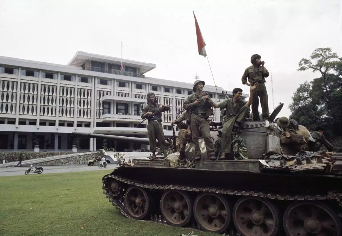 FILE- Victorious North Vietnamese troops aboard a tank take a position outside Independence Palace in Saigon, April 30, 1975, the day the South Vietnamese government surrendered, ending the Vietnam War. Communist flags fly from the palace and the tank. (AP Photo/Yves Billy, File)