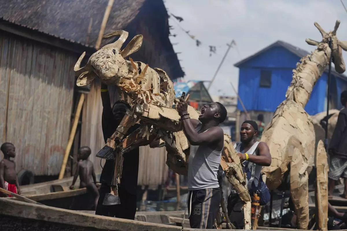Puppeteers move cardboard animals in canoes at the Makoko Slum in Lagos Nigeria, Saturday, April 19, 2025, as part of "The Herds," a moving theatre performance that started its journey from the Democratic Republic of the Congo to the Arctic Circle in a bid to bring attention to the climate crisis. (AP Photo/Sunday Alamba)