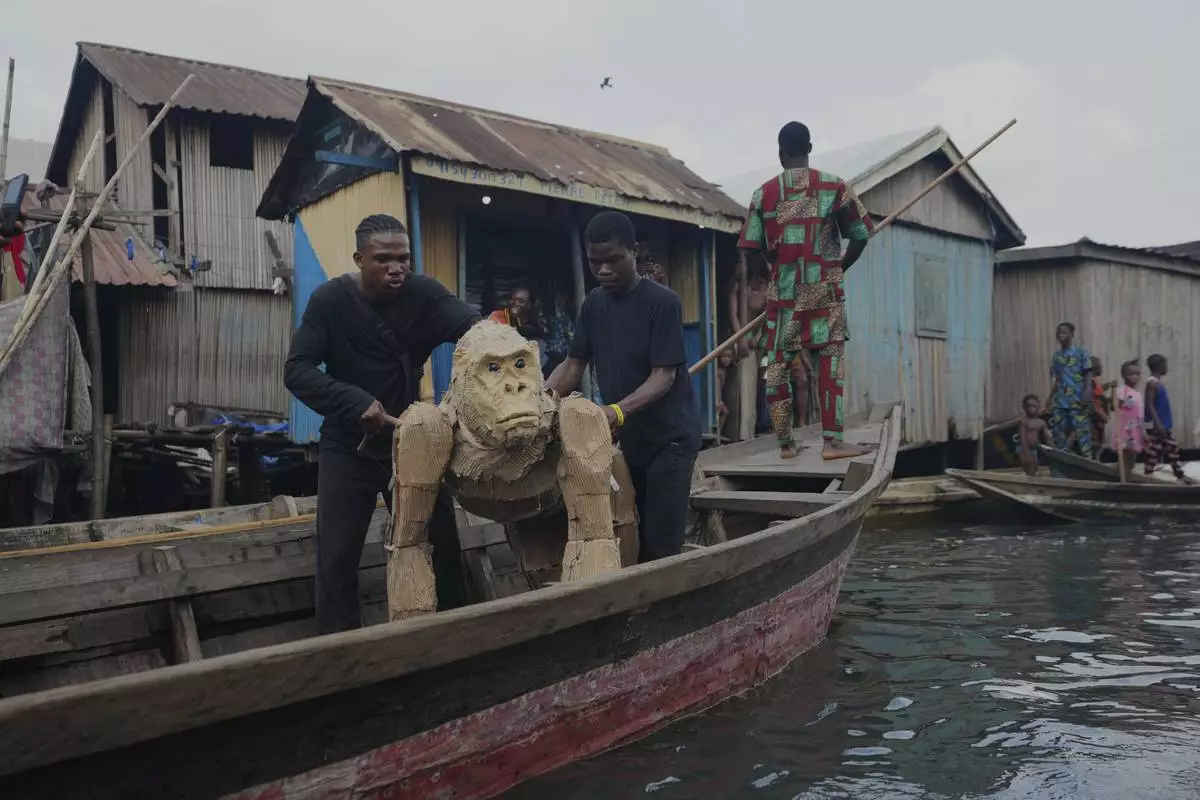 Puppeteers move cardboard animals in canoes at the Makoko Slum in Lagos Nigeria, Saturday, April 19, 2025, as part of "The Herds," a moving theatre performance that started its journey from the Democratic Republic of the Congo to the Arctic Circle in a bid to bring attention to the climate crisis. (AP Photo/Sunday Alamba)