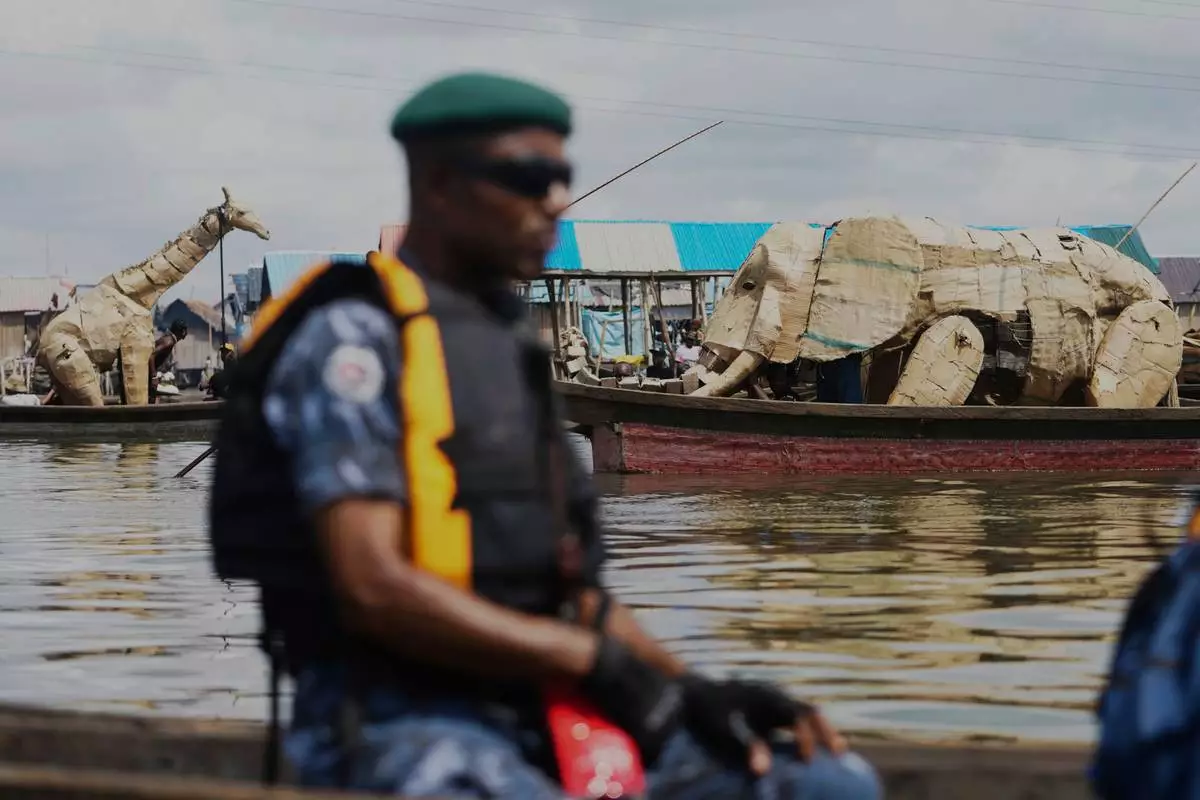 Puppeteers move cardboard animals in canoes at the Makoko Slum in Lagos Nigeria, Saturday, April 19, 2025, as part of "The Herds," a moving theatre performance that started its journey from the Democratic Republic of the Congo to the Arctic Circle in a bid to bring attention to the climate crisis. (AP Photo/Sunday Alamba)
