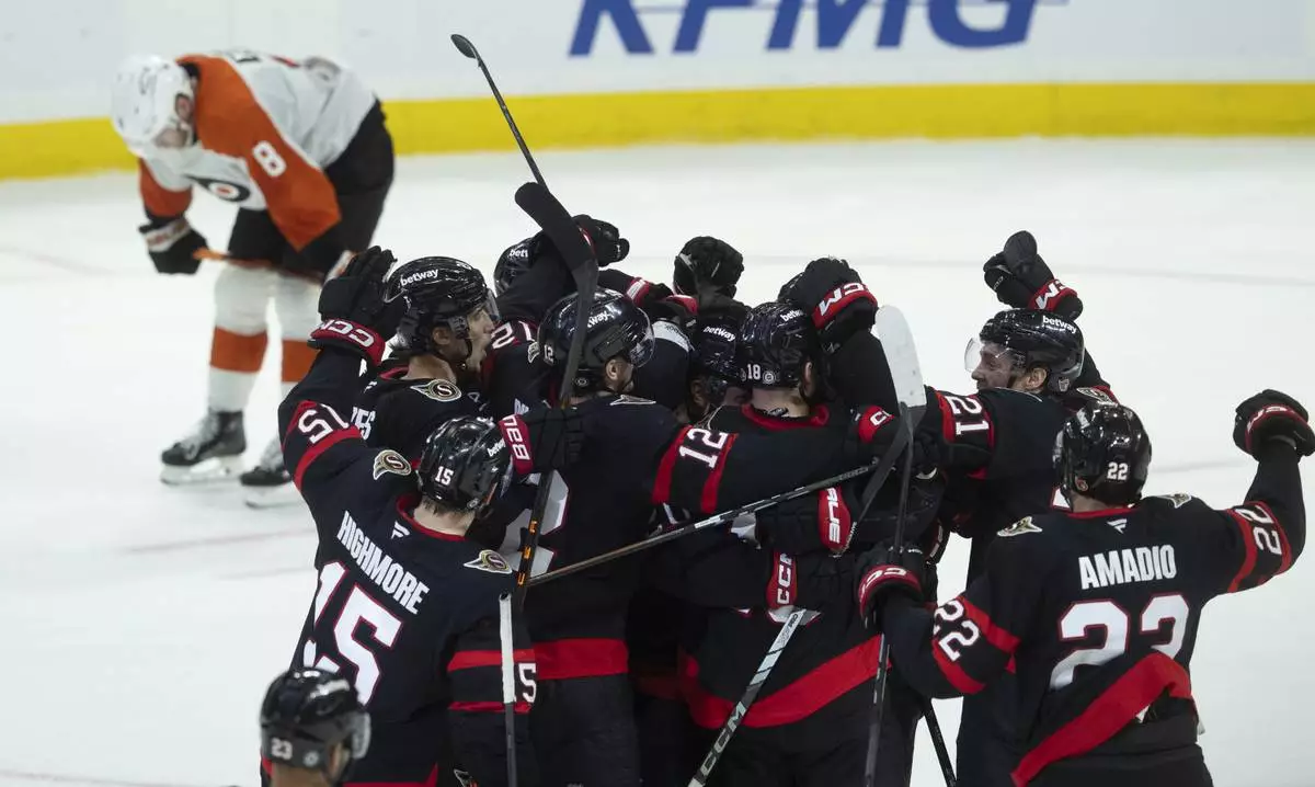 Philadelphia Flyers defenseman Cam York (8) skates past the Ottawa Senators as they celebrate their NHL hockey game overtime win in Ottawa, Sunday, April 13, 2025. (Adrian Wyld /The Canadian Press via AP)