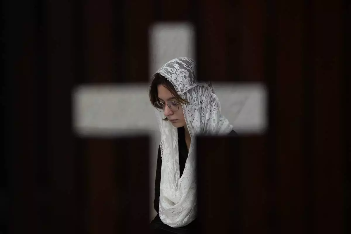 Photographed through the door of a confessional, a person prays during Mass in honor of Pope Francis, following the Vatican's announcement of his death, at the Cathedral in Brasilia, Brazil, Monday, April 21, 2025. (AP Photo/Eraldo Peres)