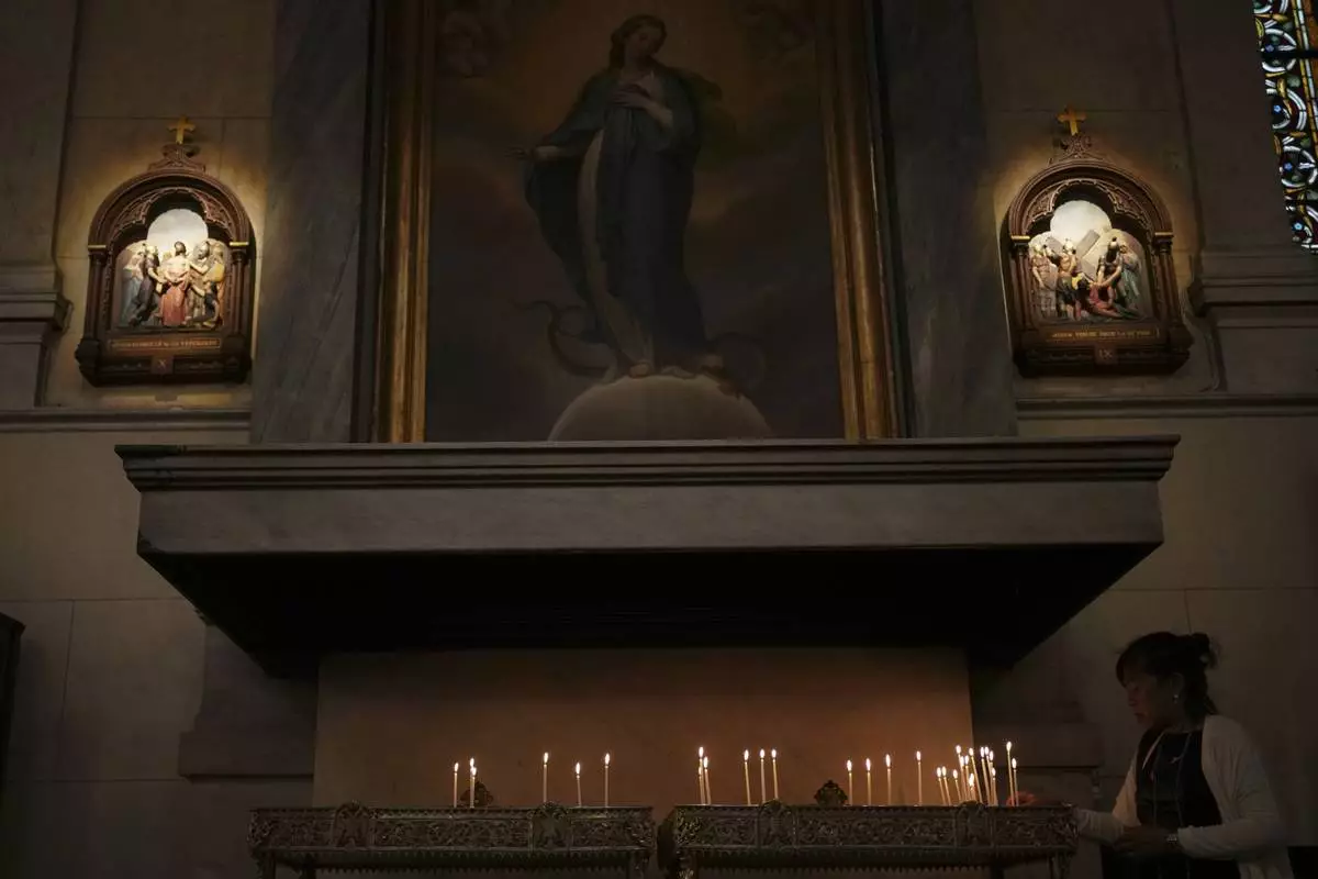 A woman lights a candle at the Catholic Cathedral Basilica of St Dionysius the Areopagite in Athens, Greece, Tuesday, April 22, 2025. (AP Photo/Thanassis Stavrakis)