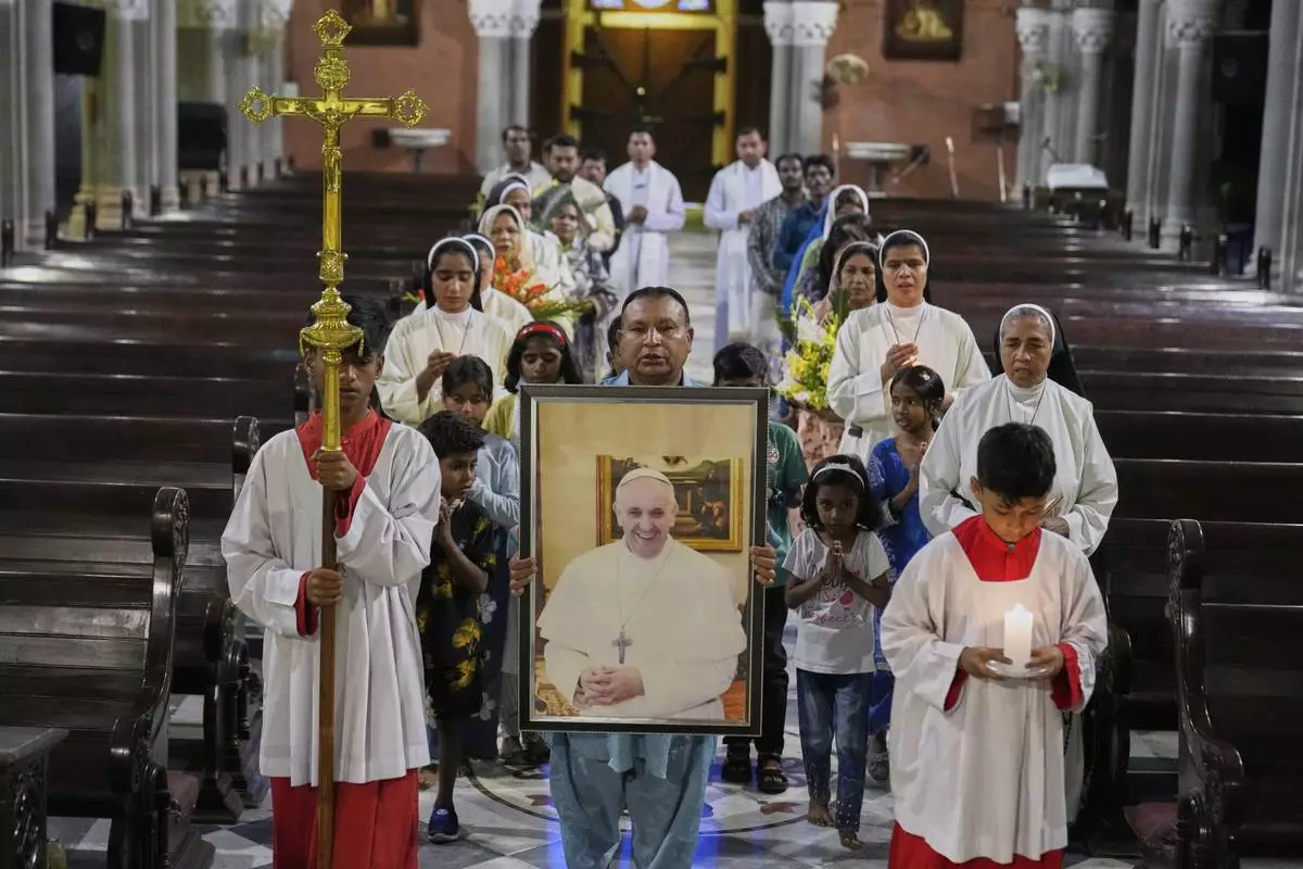 Christians arrive with a portrait of Pope Francis for a prayer ceremony at the Cathedral Church of the Resurrection, in Lahore, Pakistan Monday, April 21, 2025, following the announcement by the Vatican of the death of Pope Francis. (AP Photo/K.M. Chaudary)