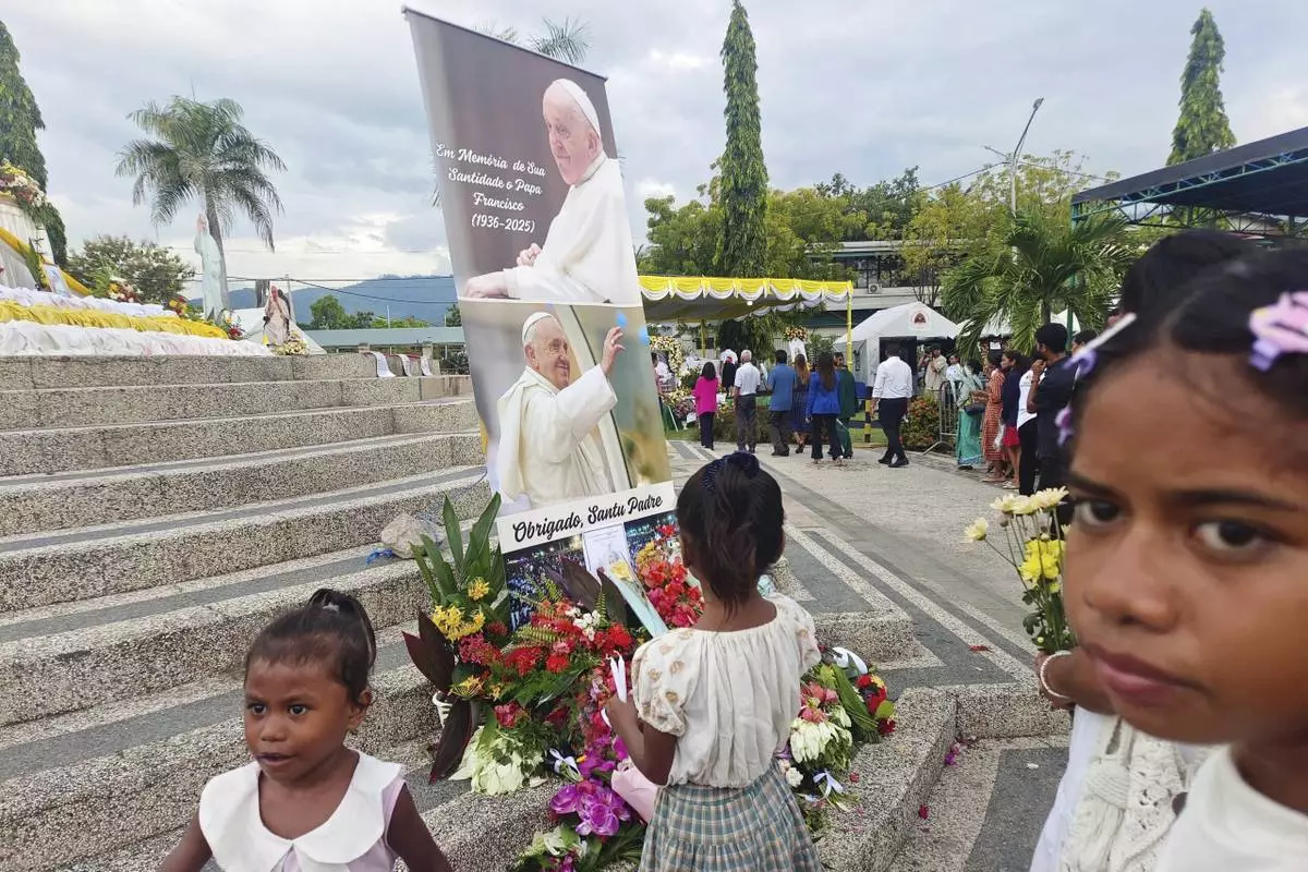 Devotees lay flowers near the banner of the late Pope Francis in Dili, East Timor, Wednesday, April 23, 2025. (AP Photo/Suzana Cardoso)