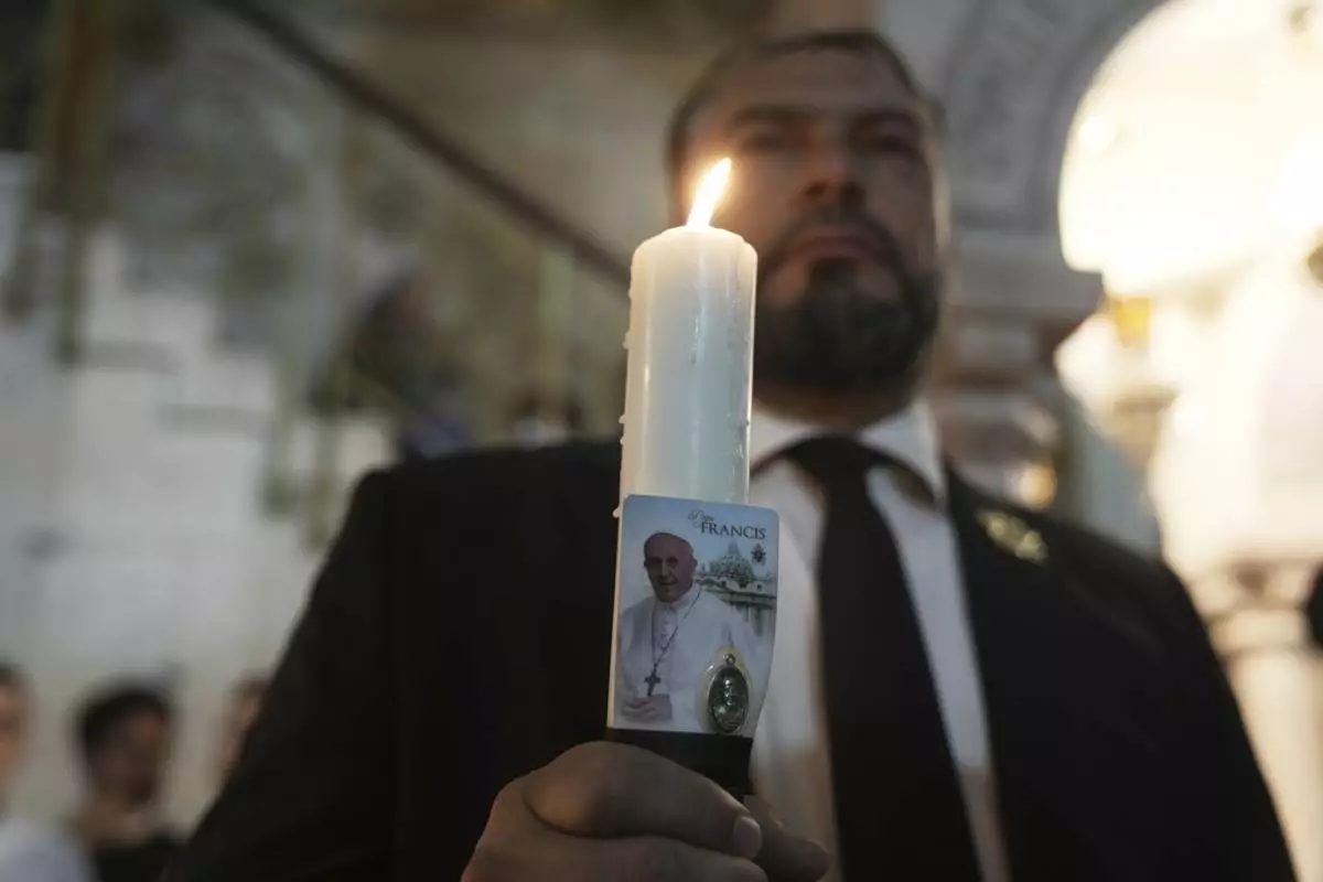 Issa Kassissieh holds a candle during a Mass led by Latin Patriarch Pierbattista Pizzaballa, the top Catholic clergyman in the Holy Land, in remembrance of Pope Francis at the Church of the Holy Sepulcher, the site where according to tradition Jesus was crucified and buried, in the Old City of Jerusalem, Wednesday, April 23, 2025. (AP Photo/Mahmoud Illean)