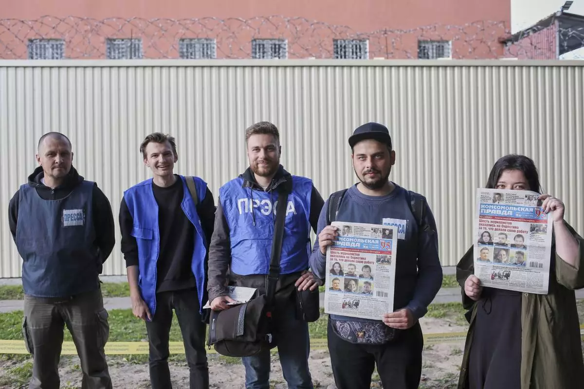 FILE - Belarusian journalists, from left, Svyatoslav Zorky, Alexey Sudnikov, Andrey Shavlyugo, Nikita Nedoverkov and Maria Eleshevich, pose after their release from a detention center, seen behind them, in Minsk, Belarus, on Sept. 4, 2020. (AP Photo, File)