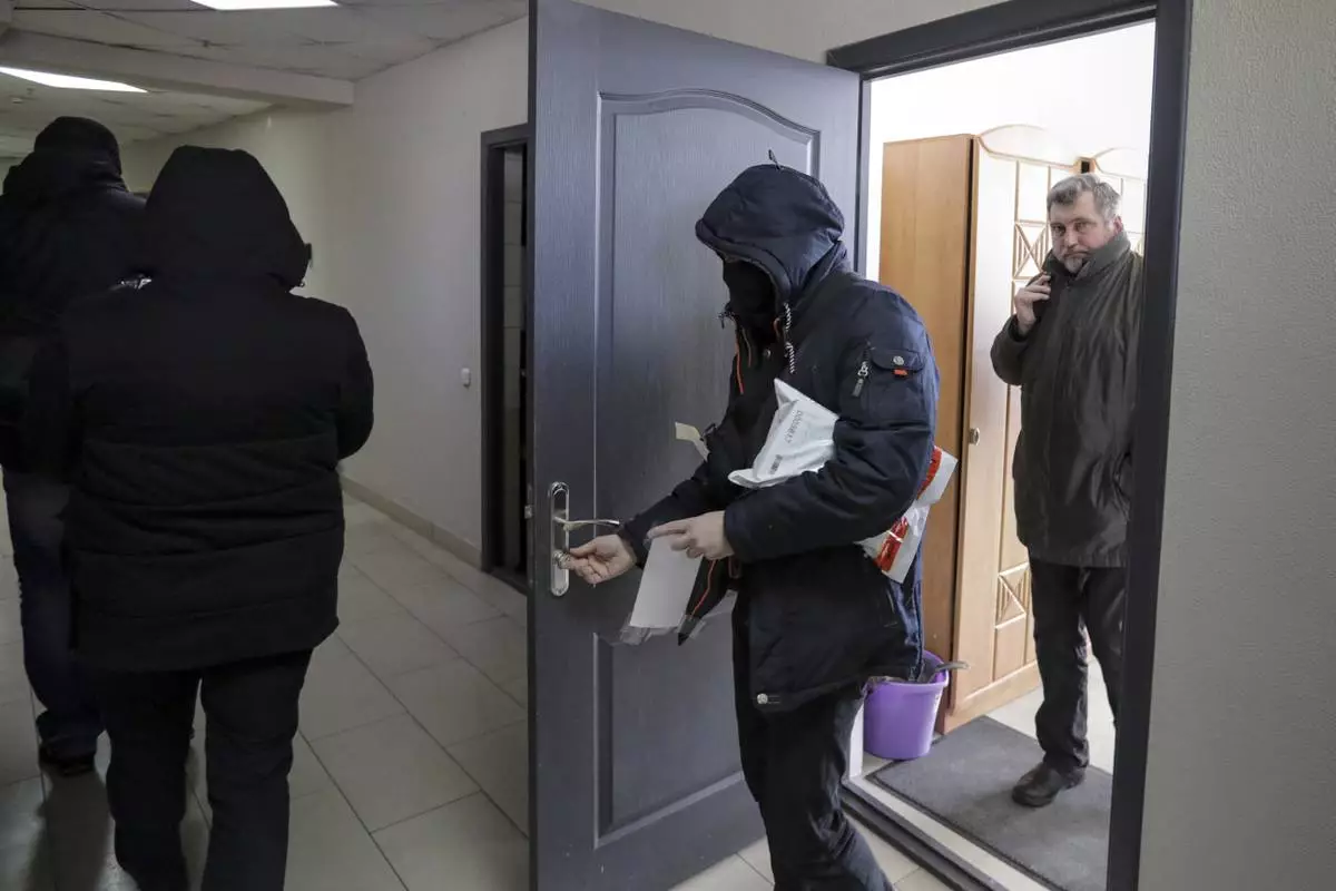 FILE - Police carry documents and computers from the office of the Belarusian Association of Journalists as Andrei Bastunets, the head the association, right, looks on in Minsk, Belarus, on Feb. 16, 2021. (AP Photo, File)