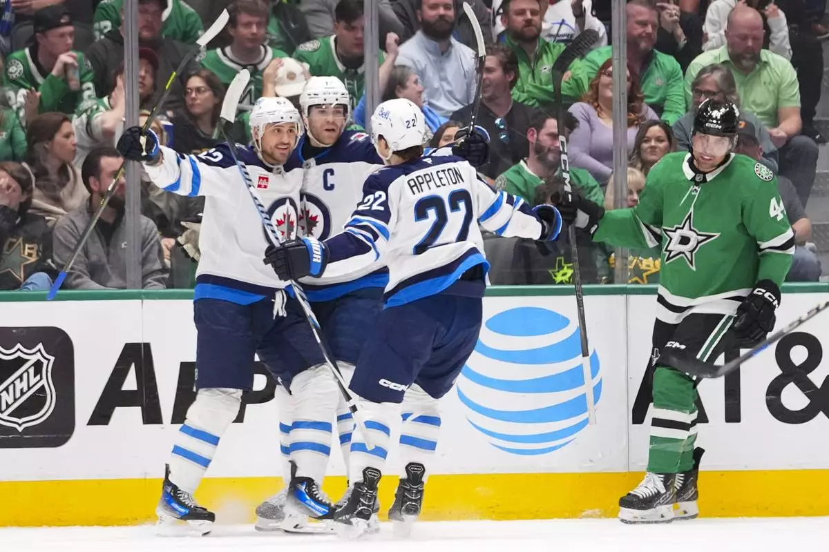 Winnipeg Jets right wing Nino Niederreiter, left, celebrates his first period goal with teammates center Adam Lowry, center, and center Mason Appleton of an NHL hockey game Thursday, April 10, 2025, in Dallas. (AP Photo/Julio Cortez)
