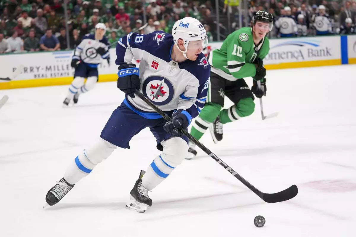 Winnipeg Jets center Jaret Anderson-Dolan (28) skates with the puck in front of Dallas Stars center Oskar Back (10) during the first period of an NHL hockey game Thursday, April 10, 2025, in Dallas. (AP Photo/Julio Cortez)