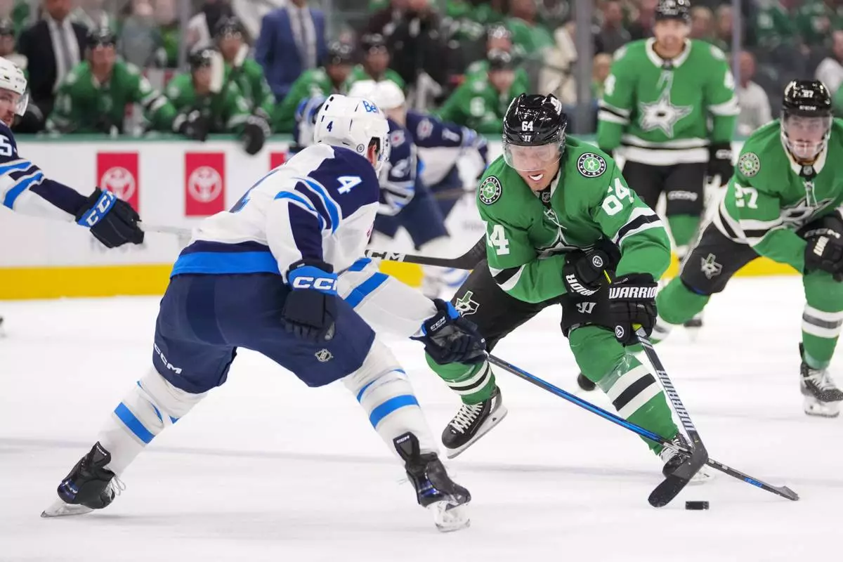 Dallas Stars center Mikael Granlund (64) attacks against Winnipeg Jets defenseman Neal Pionk (4) during the first period of an NHL hockey game Thursday, April 10, 2025, in Dallas. (AP Photo/Julio Cortez)