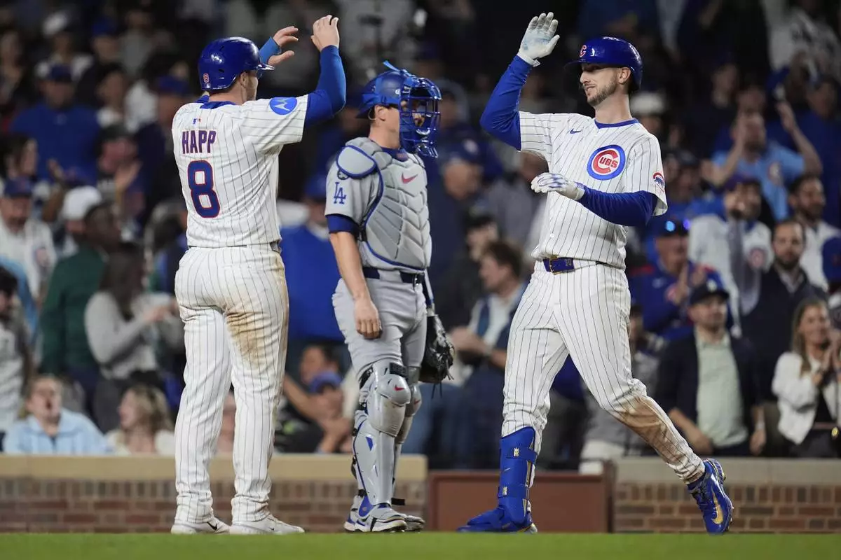Chicago Cubs' Kyle Tucker (30), right, high fives Ian Happ after Tucker hit a two-run home run during the eighth inning of a baseball game against the Los Angeles Dodgers, Tuesday, April 22, 2025, in Chicago. (AP Photo/Erin Hooley)