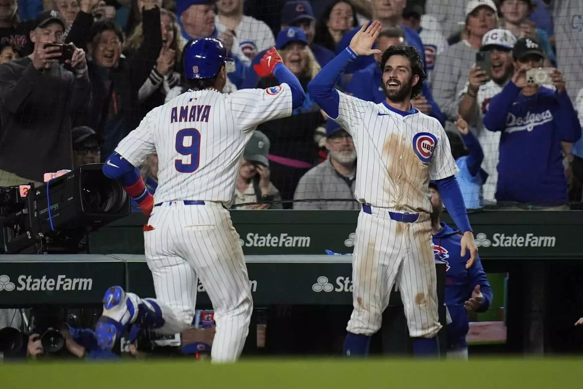 Chicago Cubs' Dansby Swanson, right, high-fives Miguel Amaya (9) after Amaya hit a game-tying home run during the ninth inning of a baseball game against the Los Angeles Dodgers, Tuesday, April 22, 2025, in Chicago. (AP Photo/Erin Hooley)