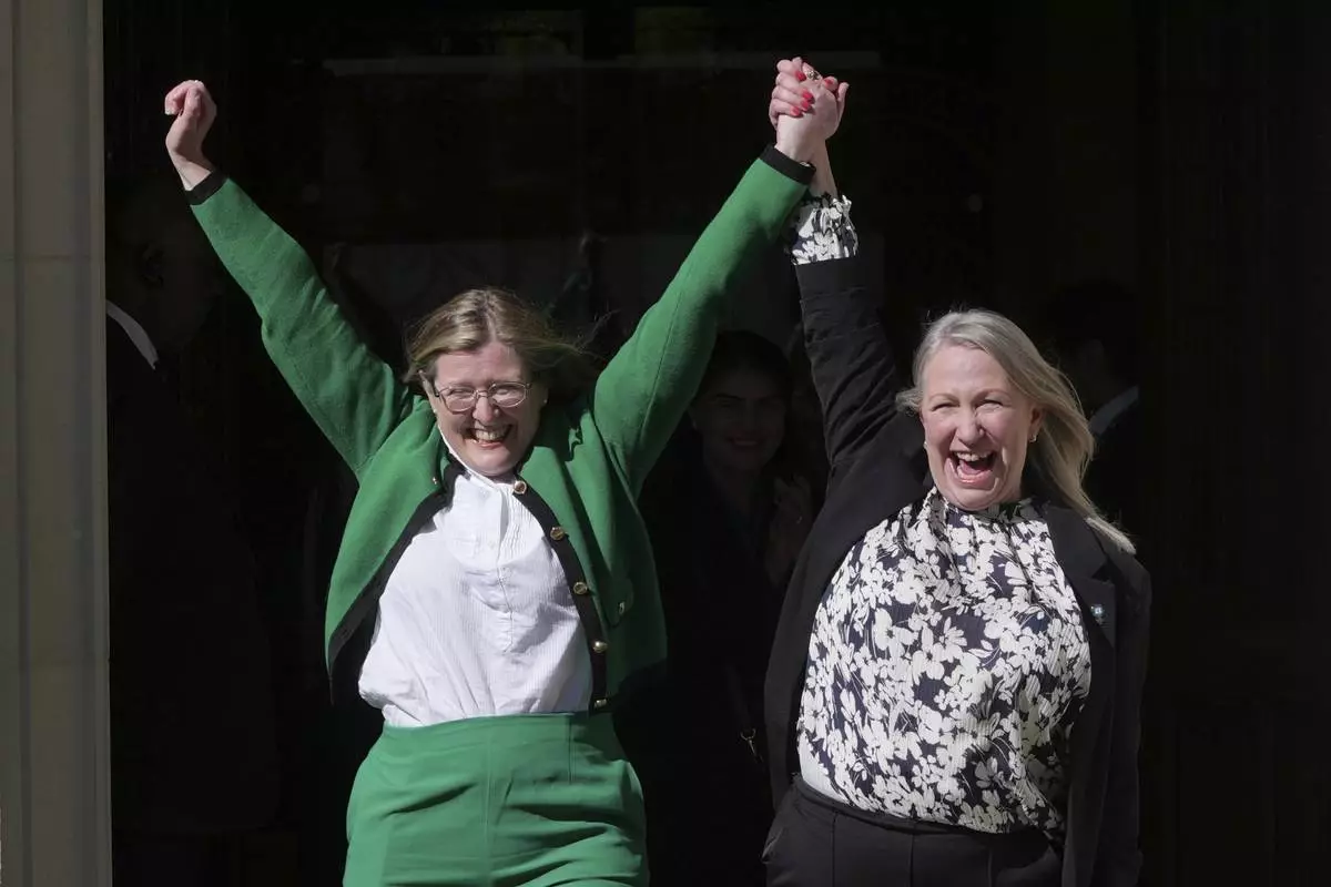 Marion Calder, right, and Susan Smith, left, from For Women Scotland, celebrate outside after the U.K. Supreme Court ruled that a woman is someone born biologically female, excluding transgender people from the legal definition in a long-running dispute between the feminist group and the Scottish government, in London Wednesday, April 16, 2025. (AP Photo/Kin Cheung)