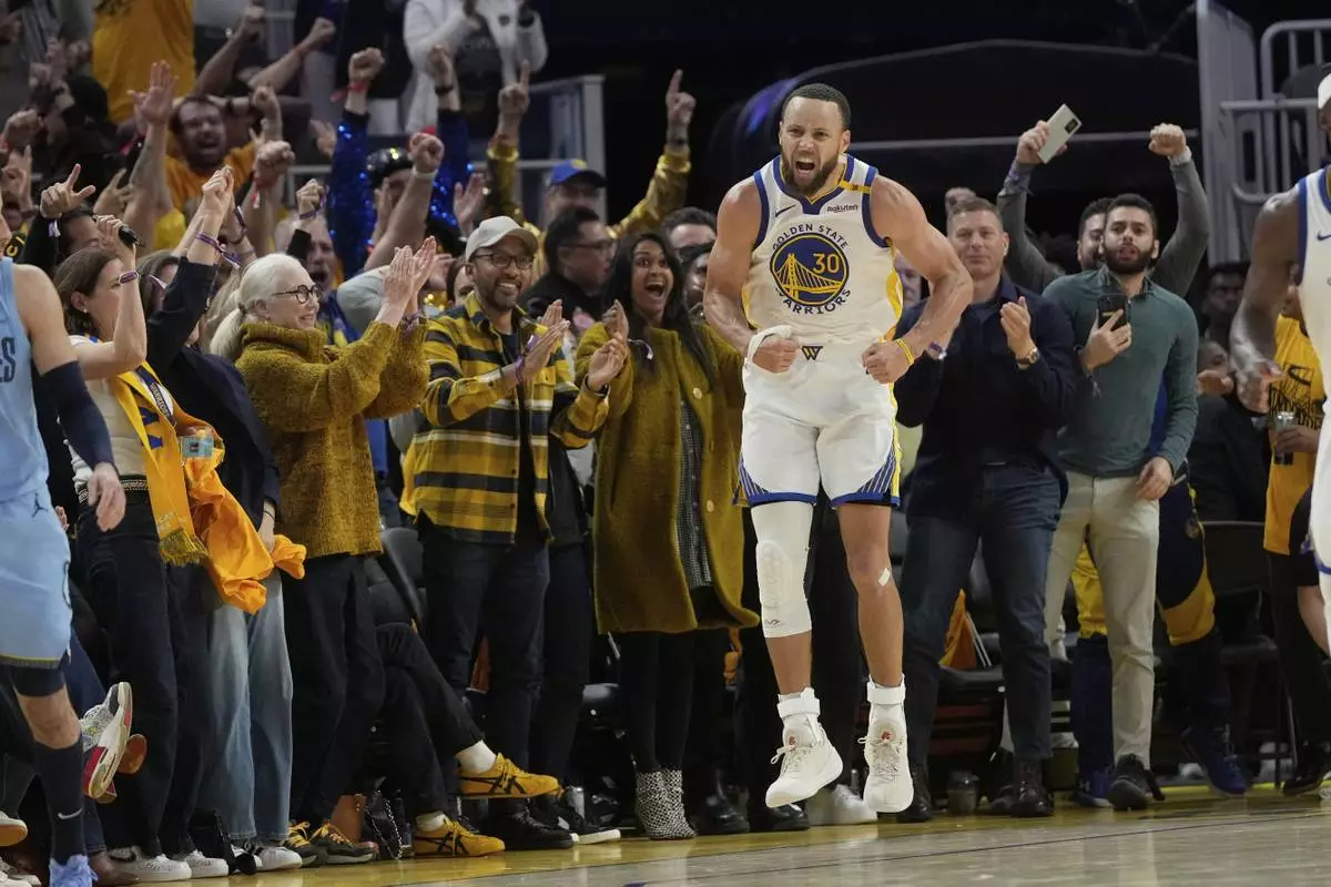 Fans react as Golden State Warriors guard Stephen Curry (30) celebrates after making a 3-point basket during the second half of an NBA play-in tournament basketball game against the Memphis Grizzlies in San Francisco, Tuesday, April 15, 2025. (AP Photo/Jeff Chiu)