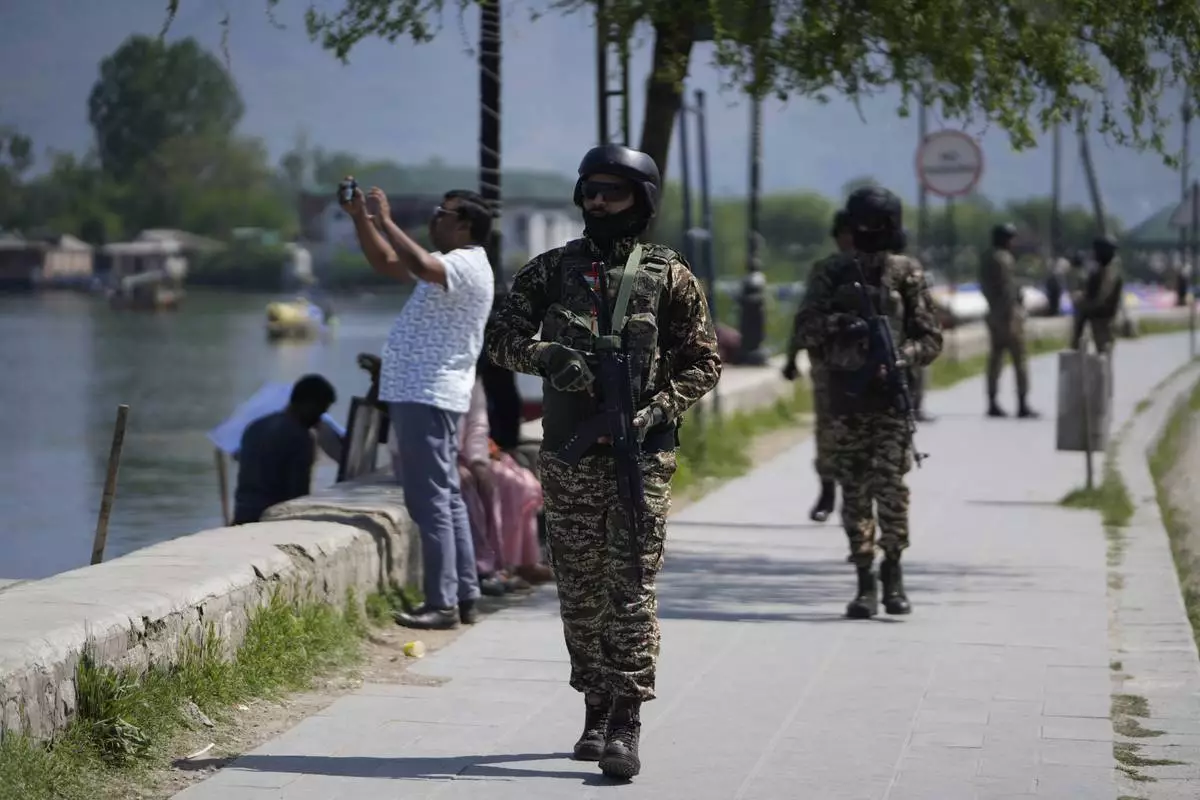 Indian soldiers guard as a tourist take picture with his cell phone on the banks of Dal Lake in Srinagar, Indian controlled Kashmir, Thursday, April 24, 2025. (AP Photo/Mukhtar Khan)