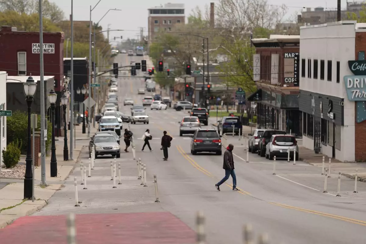 People cross 31st Street in Kansas City, Mo., where the city implemented a "road diet" reducing the street from four lanes to two in an effort to reduce speeding and accidents, Thursday, April 17, 2025. (AP Photo/Charlie Riedel)
