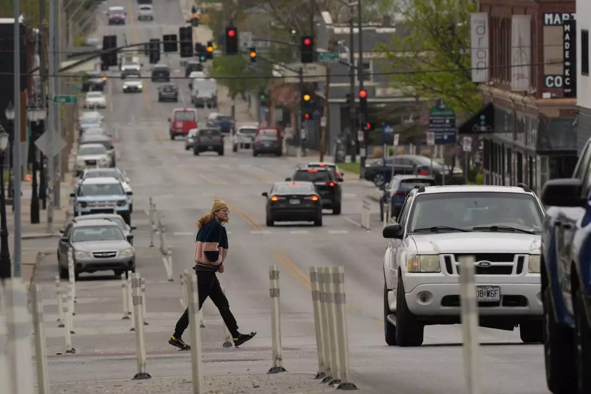 A man crosses 31st Street in Kansas City, Mo., where the city implemented a "road diet" reducing the street from four lanes to two in an effort to reduce speeding and accidents, Thursday, April 17, 2025. (AP Photo/Charlie Riedel)