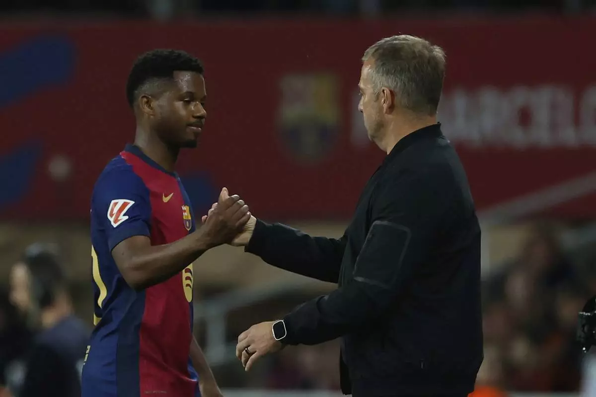 Barcelona's head coach Hansi Flick, right, greets Barcelona's Ansu Fati after he is substituted by Barcelona's Raphinha during a Spanish La Liga soccer match between Barcelona and Mallorca at the Lluis Companys Olympic stadium in Barcelona, Spain, Tuesday, April 22, 2025. (AP Photo/Joan Monfort)
